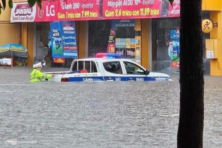 Nước ngập  ngang thân xe của cảnh sát giao thông ở TP Uông Bí, tràn vào nhà dân hai bên đường.