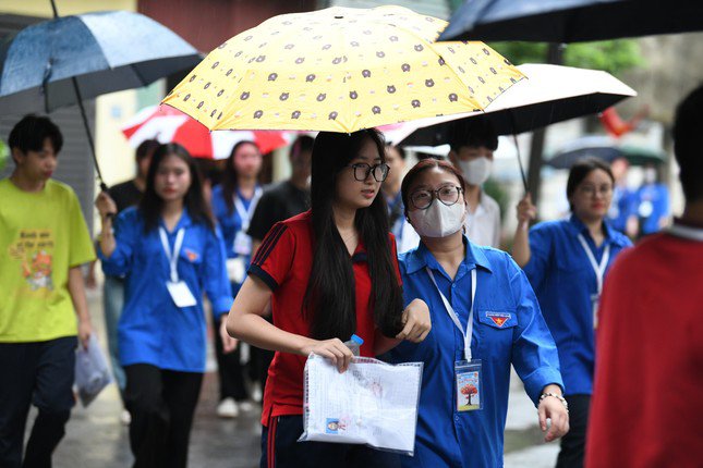 40 tình nguyện viên của Trường THPT Khương Đình và bên điểm Trường Khương Hạ mang ô che cho các thí sinh trước khi vào điểm thi. Ảnh: Như Ý