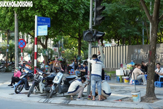 Đơn vị thi công đang lắp đặt trụ đèn tín hiệu giao thông tại nút giao Phạm Văn Bạch - Hoàng Quán Chi, chiều 13/.6