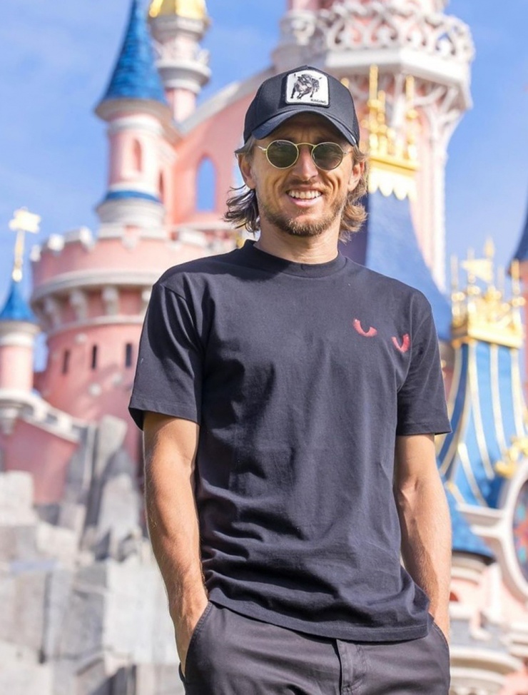 Siêu sao chọn set đồ nhấn vào kính mát và mũ lưỡi trai khi vui chơi ở Disneyland, Paris, Pháp cùng gia đình.