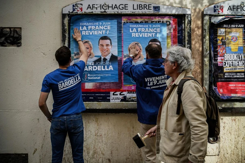 Tình nguyện viên đảng Mặt trận Quốc gia Pháp dán ảnh vận động bầu cử cho bà Le Pen và ông Bardella, tại Lyon (Pháp). Ảnh: AFP