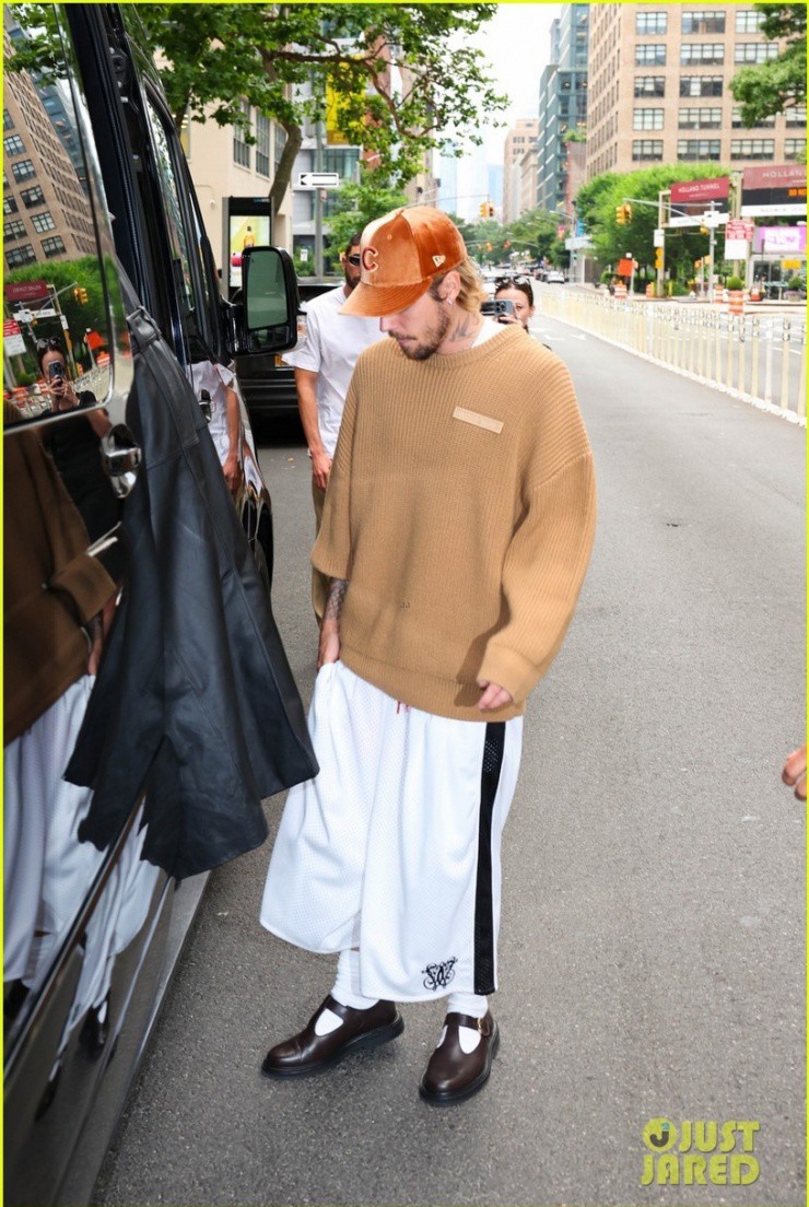 Trong khi đó, Justin mặc quần lửng trắng sọc đen, áo sweater màu nâu vàng và đội mũ lưỡi trai nhung màu cam.
