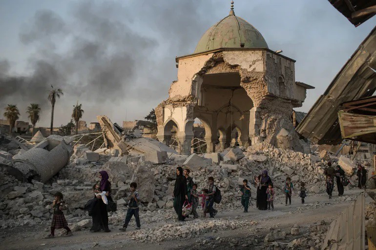 Người dân Iraq đi ngang qua đền thờ al-Nuri bị IS tàn phá nặng nề (ảnh: Al Jazeera)