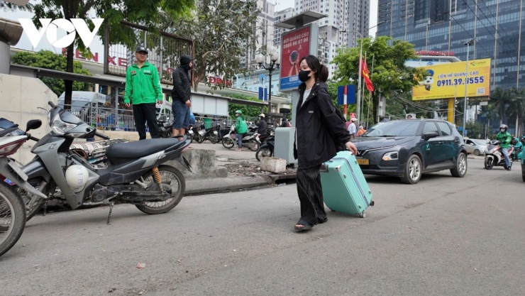 Nhiều hành khách tay xách vali, có mặt tại khu vực bến xe để lên xe khách về quê nghỉ lễ.