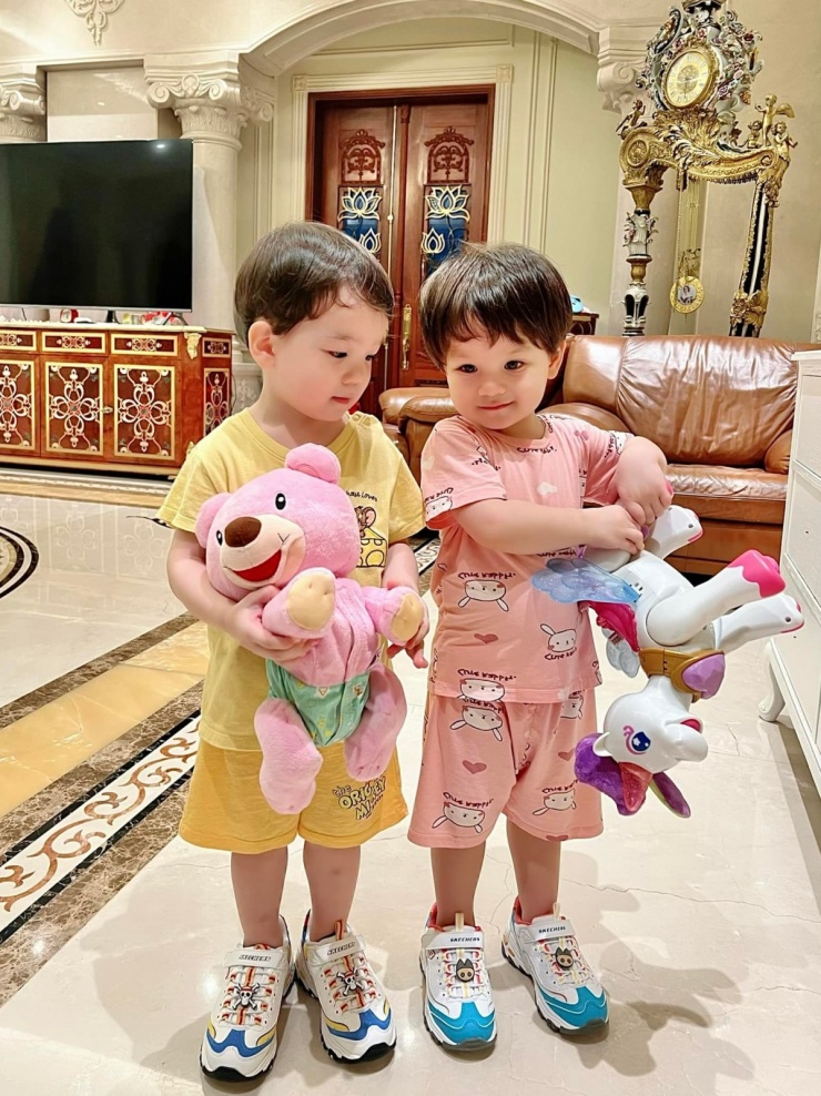 Phòng khách nổi bật với trần cao. Nội thất gồm sofa bọc da, tranh trang trí cùng các chi tiết như bàn trà, thảm trải sàn được phối hợp hài hòa, tạo tổng thể thống nhất. Tông màu nâu ấm từ chất liệu da và gỗ giúp không gian thêm phần ấm cúng. Một chiếc đồng hồ cây kiểu cổ điển đặt ở góc phòng trở thành điểm nhấn.