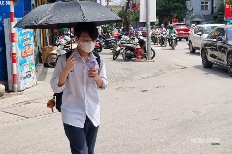 Học sinh dùng quạt tích điện mini để giảm nóng khi đi bộ ngoài trời.