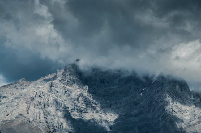 Mây đen bao phủ đỉnh núi tuyết trắng trong vườn quốc gia Banff.