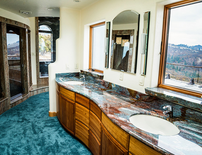 Một trong những phòng tắm có mặt bàn bằng đá được đánh bóng và tầm nhìn tuyệt đẹp ra phía ngoài cửa sổ