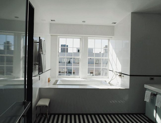 Một trong những phòng tắm có tầm nhìn ra thành phố sôi động. Bồn tắm hình vuông lớn đặt ở phía trước cửa sổ với nước chảy trực tiếp từ vòi phun gắn liền trên trần nhà