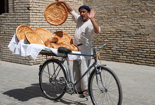 Bánh mì Uzbekistan: &#34;Mua bánh mì đi! Nó vẫn còn ấm và mỗi ổ bánh là duy nhất chỉ có ở Uzbekistan&#34; Một người đàn ông bán bánh mì ở Buchara, Uzbekistan đang rao to trên tay cẩm ổ bánh mì khổng lồ chỉ có ở quốc gia này.