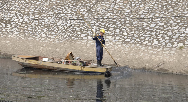 Công nhân Công ty Thoát nước Hà Nội đang vớt rác trên sông Tô Lịch. (Ảnh: Thành An)