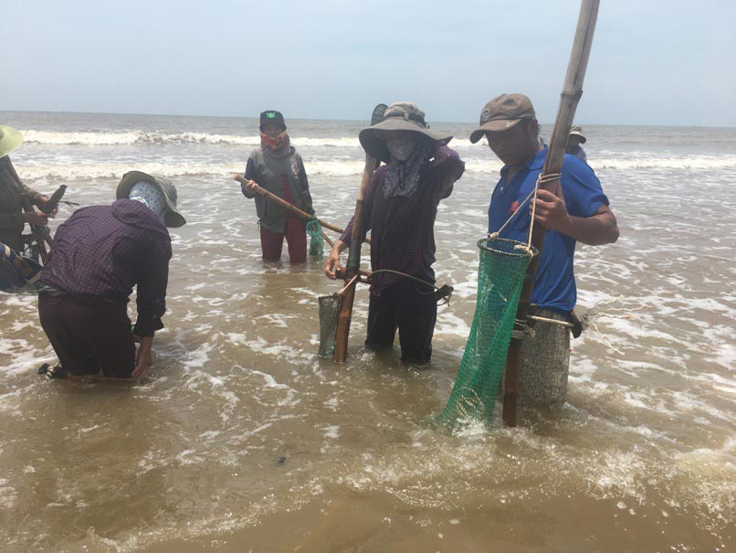 Ngư dân chuẩn bị rửa dụng cụ để về nhà sau 4 tiếng dầm mình trong nước biển để cào ngao. Ảnh: Cảnh Thắng.