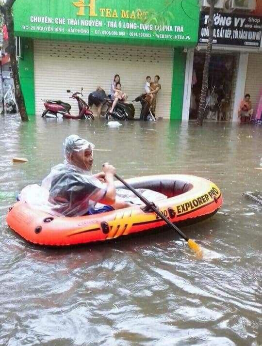 Một nam thanh niên mang thuyền ra làm phương tiện di chuyển khi phố Nguyễn Bình đã thành "sông".