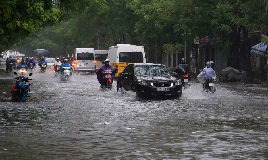 Người dân di chuyển qua phố Bạch Đằng bị ngập, úng.