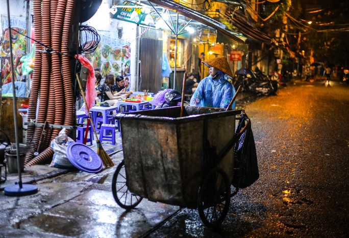 Những công nhân môi trường đô thị vẫn miệt mài thu gom rác trong đêm, từng nhát chổi nặng trĩu dưới mưa