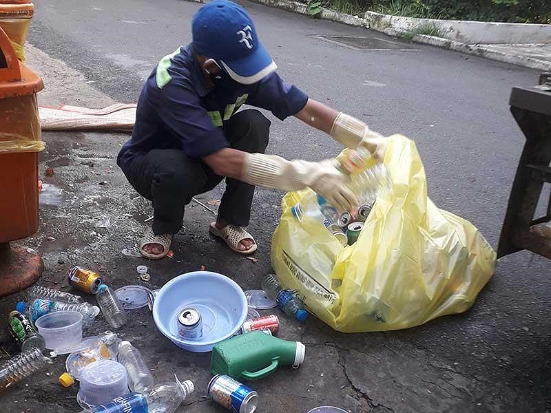Công nhân vệ sinh trong BV Phạm Ngọc Thạch lựa chai nhựa nằm lẫn trong túi màu vàng ghi dòng chữ&nbsp;“Chất thải lây nhiễm” rồi để riêng. Ảnh: TRẦN NGỌC&nbsp;