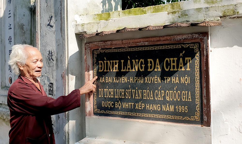 Cụ Đoán chỉ tay vào tấm biển Đình làng Đa Chất và cho biết, hai báu vật của làng là cối xay và tiếng lóng