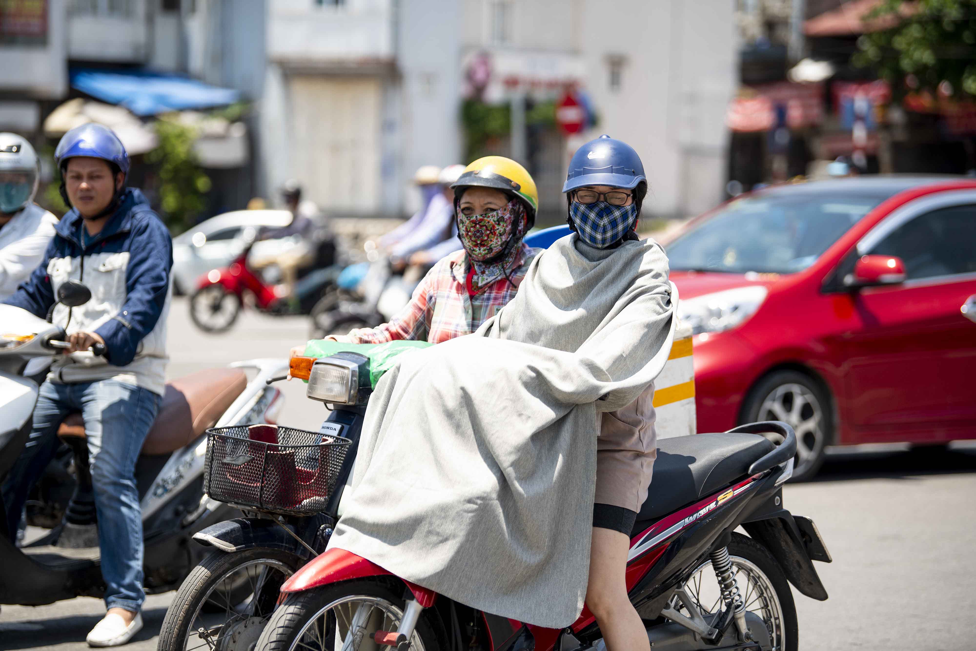 Một phụ nữ đi xe máy dùng nguyên cái chăn để chống nắng khi tham gia giao thông giữa trời nắng 38 độ.&nbsp;