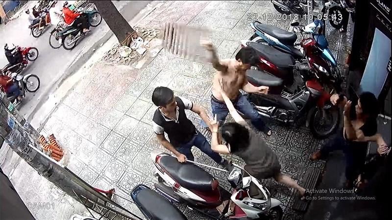 Hình ảnh camera an ninh cho thấy người đàn ông hàng xóm cầm bậc tam cấp gỗ tấn công hàng xóm. Ảnh cắt từ clip.