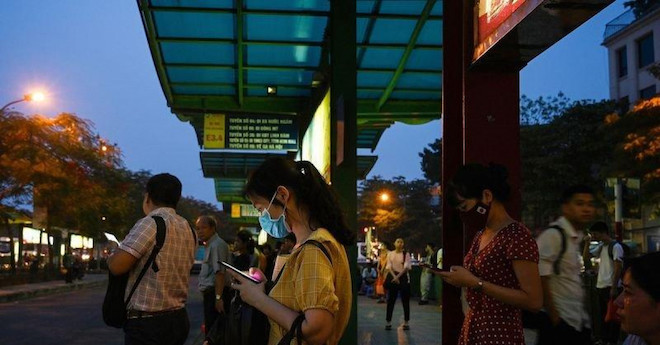 Người dân sử dụng điện thoại di động tại một trạm dừng xe buýt. Ảnh: Getty Images