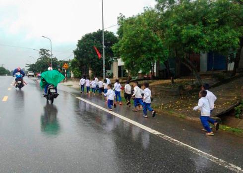 Trời mưa nhỏ, các em cùng nhau chạy trên đường QL9.