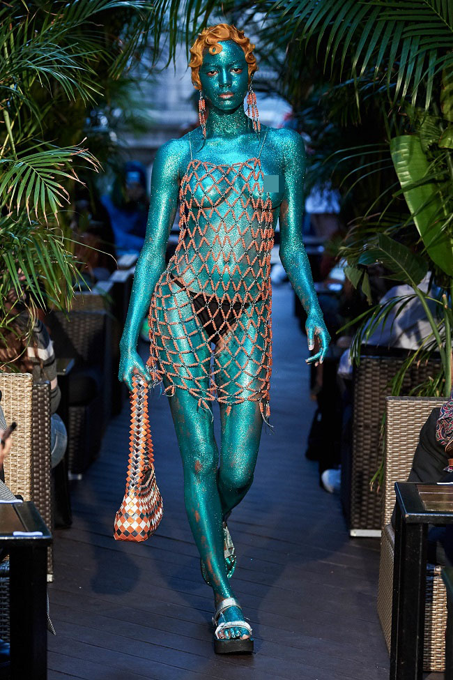 Người mẫu tô vẽ xanh người và thả rông trên sàn catwalk.