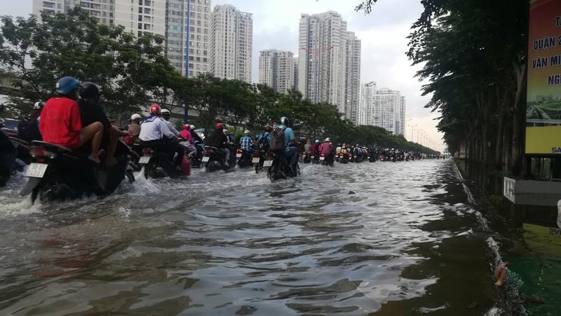 Nước ngập sâu nên các phương tiện (chủ yếu là xa máy) dồn sang mép trái của làn đường để di chuyển.&nbsp;