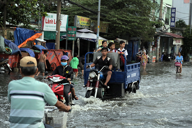 Nhóm học sinh vượt qua “hồ bơi” trên phố Sài Gòn bằng phương tiện xe ba gác máy.