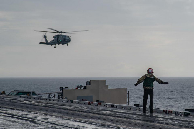 Kỹ thuật viên điện tử hàng không James Benzel, đến từ bang Ohio, ra hiệu cho chiếc MH-60R Seahawk hạ cánh trên boong tàu sân bay USS Ronald Reagan. Ảnh: Hạm đội 7 Mỹ