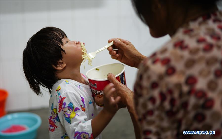 Một em bé đang được cho ăn mỳ ăn liền ở nơi tránh trú khi xảy ra vỡ đê tại Phiên Dương, Giang Tây (ảnh: Xinhua)