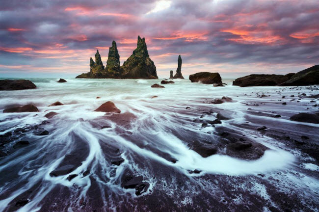 Reynisdrangar, Iceland:&nbsp;Bãi biển gần ngôi làng Vík í Mýrdal gây ấn tượng với núi đá bazan bao gồm 3 đỉnh cao 66m. Theo truyền thuyết Iceland, chúng là hài cốt của những người khổng lồ xấu số.
