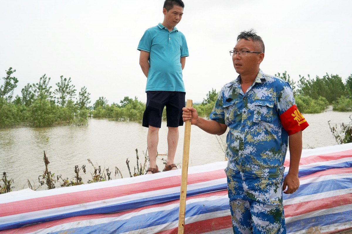 Kỹ sư thủy lực Liu Liangwu (đeo băng đỏ trên tay) kiểm tra đoạn đê bao quanh thị trấn Giang Châu. Ảnh: SCMP