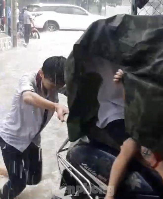 Hai em học sinh giúp dân vượt ngập giữa mưa lớn (Ảnh: cắt từ clip)