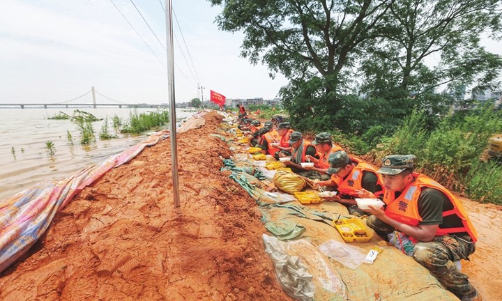 Binh sĩ Trung Quốc ăn cơm ngay trên đê (ảnh: Xinhua)