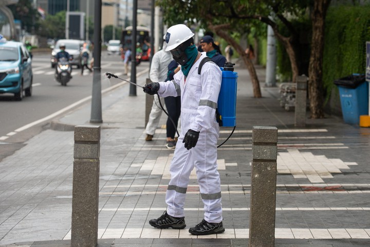 Nhân viên y tế phun thuốc khử trùng trên đường phố ở Indonesia (ảnh: Reuters)