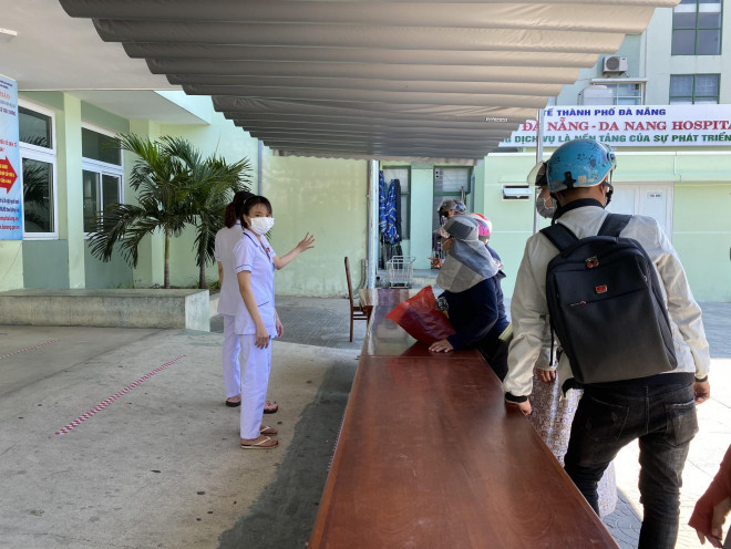 Người nhà bệnh nhân đứng bên ngoài liên hệ với nhân viên y tế sau giờ cách ly tại Bệnh viện Đà Nẵng