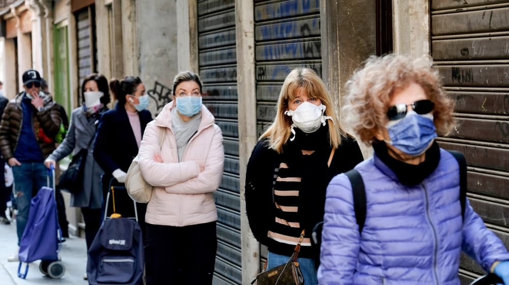 Người dân thành phố Venice, Italia đeo khẩu trang, tuân thủ khoảng cách an toàn khi xếp hàng trước một chợ cá. Ảnh: Reuters