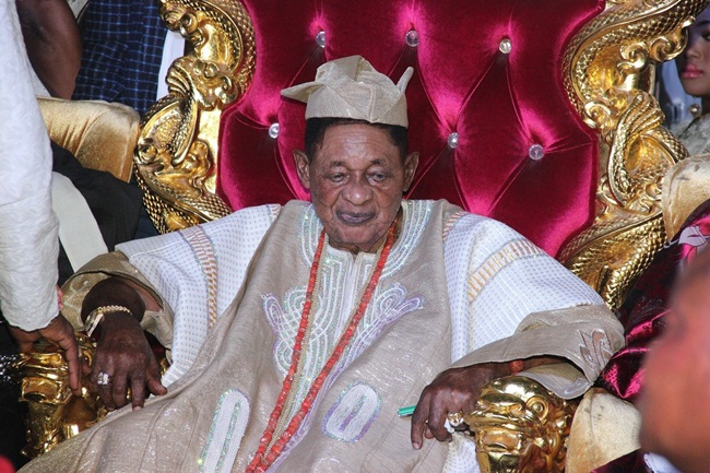 Ông là Alaafin - vua&nbsp;vương quốc Oyo của người&nbsp;Yoruba tại Nigeria và được nhiều người biết đến với bộ sưu tập xe hơi đắt tiền.
