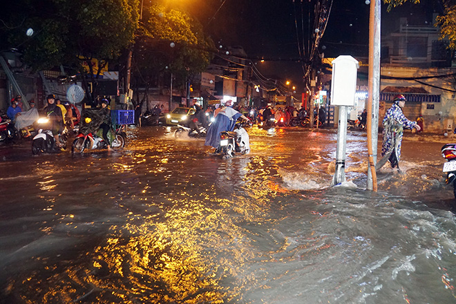 Người dân tấp xe hai bên đường để chờ nước rút mới dám về nhà, số khác phải hì hục lau chùi bugi hoặc dẫn bộ phương tiện trong dòng nước.