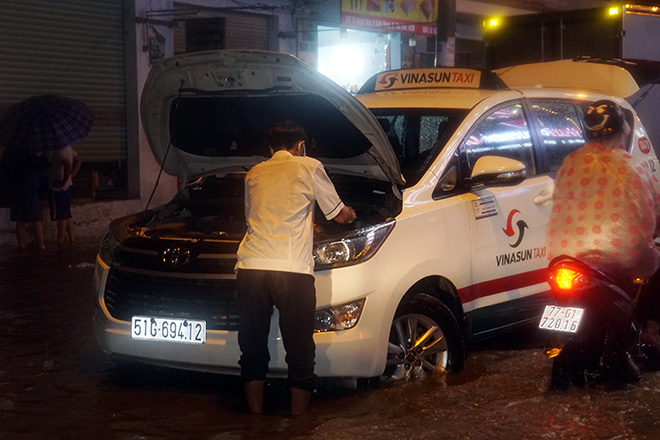 “Bơi” trong nước ngập trên đường, phương tiện chết máy khiến tài xế taxi mệt mỏi.