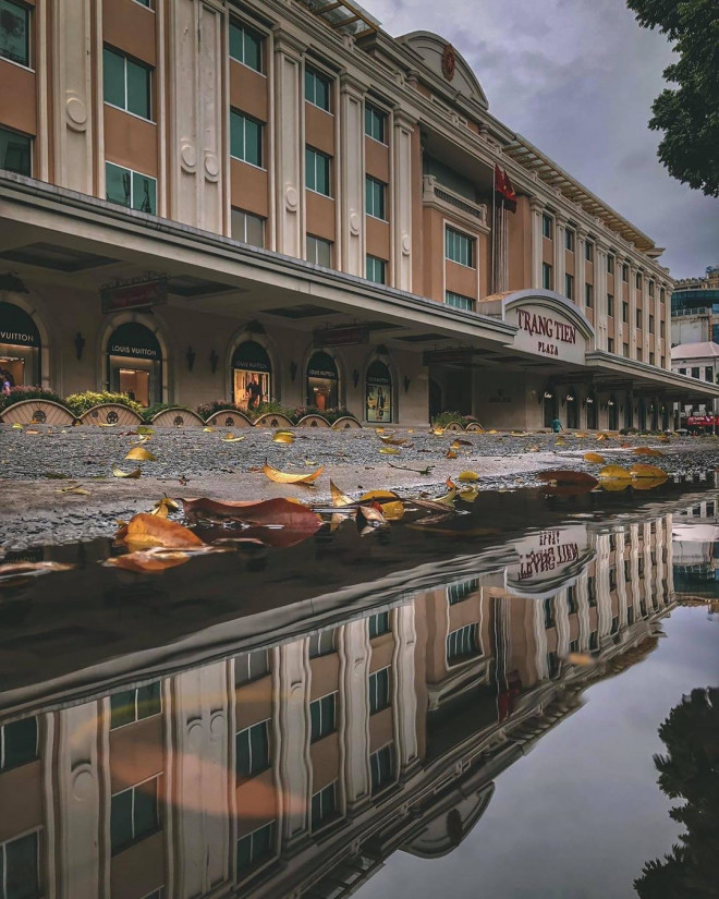 Tràng Tiền Plaza trở nên lãng mạn hơn khi được phản chiếu qua vũng nước mưa. Ảnh: Đức Nguyễn