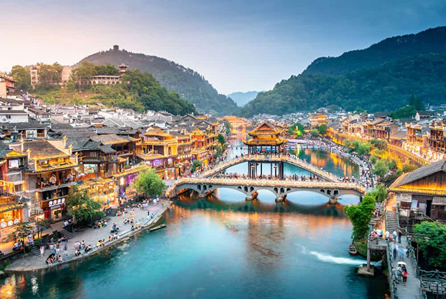 Phượng Hoàng cổ trấn: Nằm ở tỉnh Hồ Nam, đây là một trong những thị trấn cổ nổi tiếng và ấn tượng nhất để tham quan ở Trung Quốc. Phượng Hoàng cổ trấn mang đến cảm giác nhộn nhịp và hơi thở cổ xưa bên cạnh phong cảnh, kiến trúc đẹp mê hồn. 
