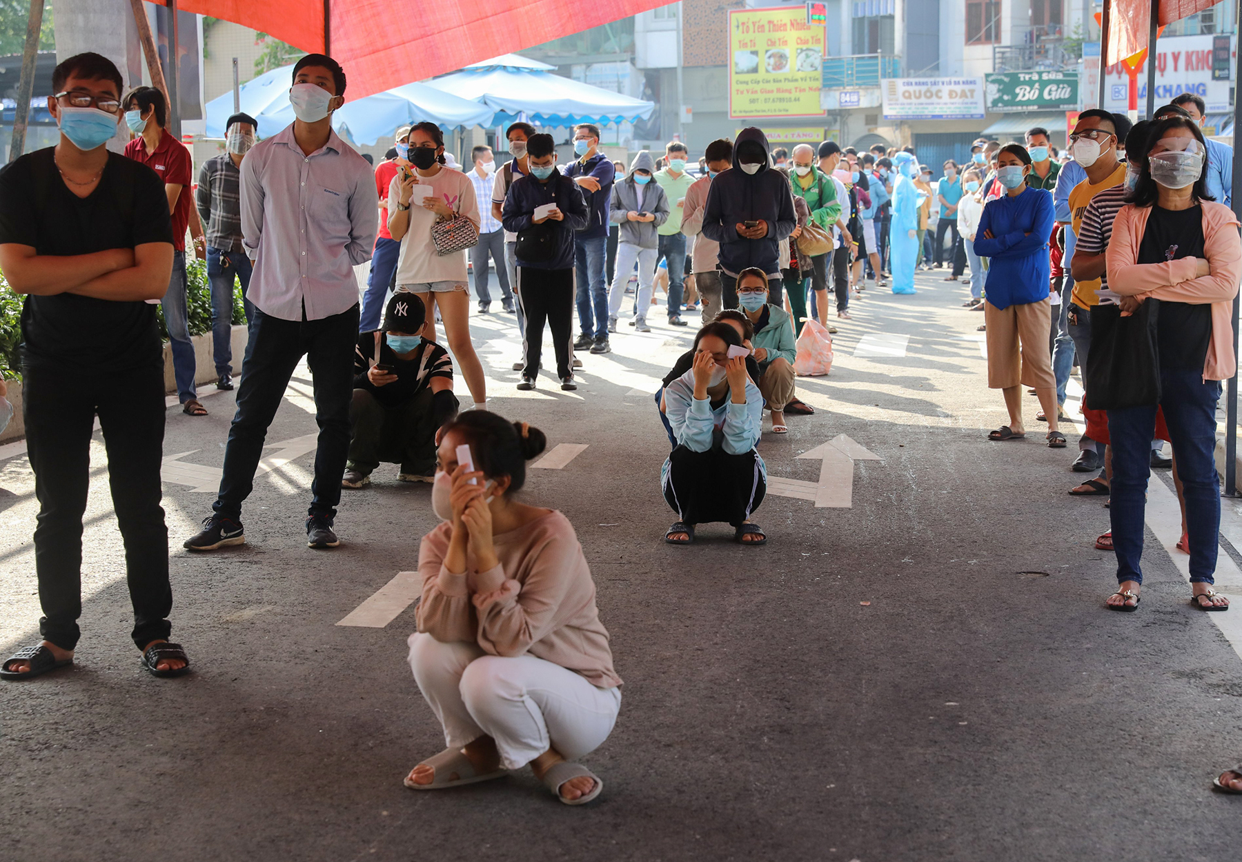 Chờ đợi lâu, một số người phải ngồi cho đỡ mỏi chân để đợi đến lượt lấy mẫu. “Văn phòng làm việc ở thành phố nhưng thỉnh thoảng tôi phải xuống xưởng ở Đồng Nai. Cần có giấy xét nghiệm âm tính với SARS-CoV-2 nên hôm nay tôi phải đi xét nghiệm để mấy hôm tới đi lại cho thuận tiện”, chị Nguyễn Bích Ngọc, ngụ TP Thủ Đức cho hay.