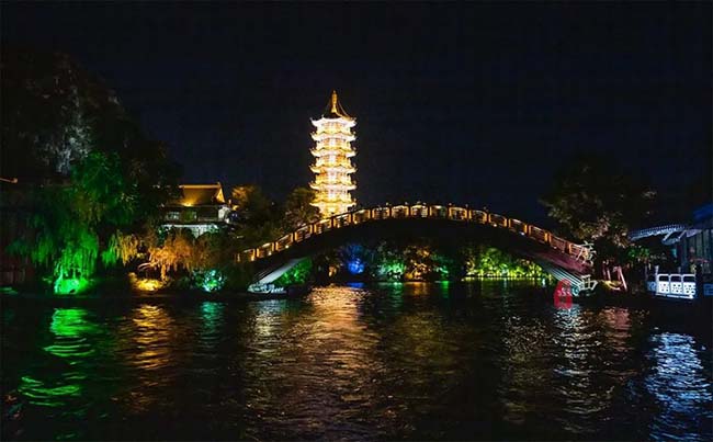 Đây là cầu Rongxi, dài 26m, rộng 8m, nằm ở giao điểm hồ Lize và hồ Rong. Cây cầu này giống với cây cầu Triệu Châu nổi tiếng, mặt cầu trắng như pha lê, thân cầu trong suốt. Mặc dù là ban đêm nhưng bạn vẫn thấy có rất nhiều cây xanh, đặc biệt là ngôi chùa sừng sững phía sau đầy kiêu hãnh.
