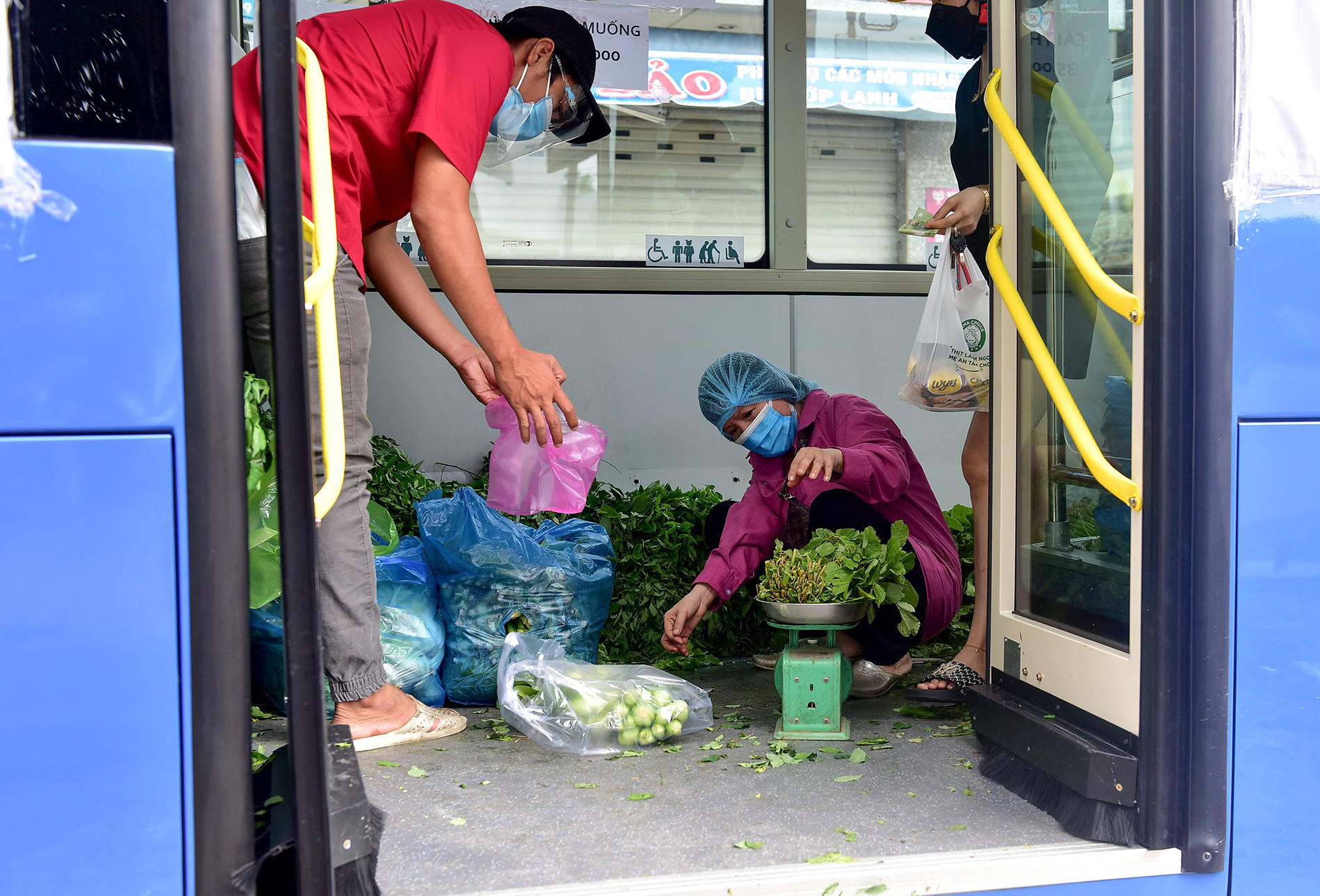 Một nhân viên bán sẽ cân rau củ cho khách ngay trước cửa ra.