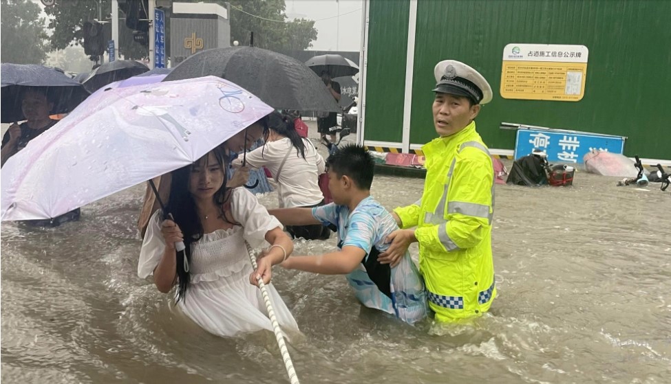 Một cảnh sát giao thông hướng dẫn người dân thành phố Trịnh Châu băng qua con đường ngập nước bằng một sợi dây. Ảnh: Reuters