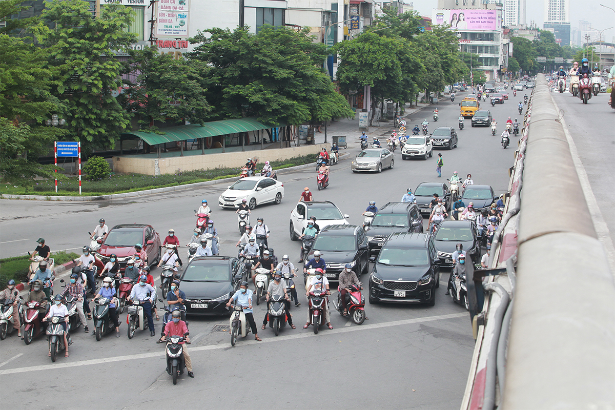 Người dân chờ đèn đỏ dưới chân cầu vượt Ngã Tư Sở (quận Đống Đa) vào sáng nay.