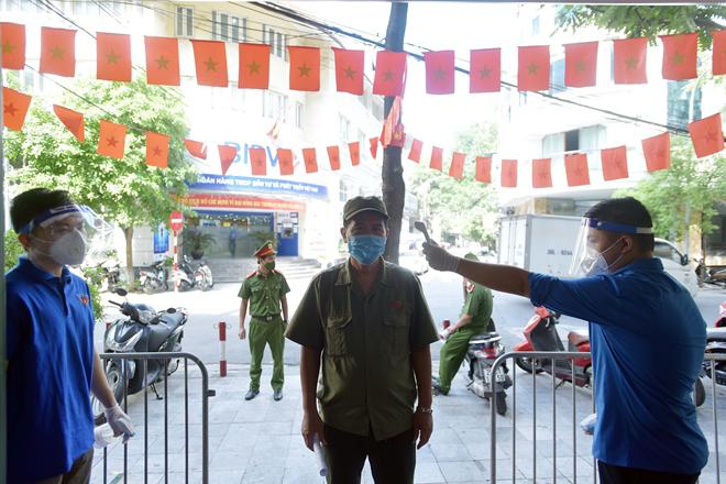 Người dân theo danh sách đăng ký được thông báo đến điểm tiêm chung, tất cả đều phải tiến hành đo thân nhiệt, sát khuẩn tay trước khi vào khu vực tiêm.