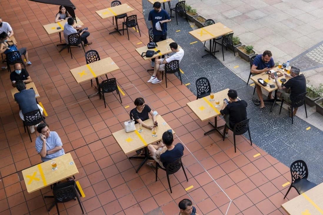 Khách hàng tại một nhà hàng ngoài trời có bàn ăn tuân thủ khoảng cách an toàn ở Singapore. Ảnh: Bloomberg