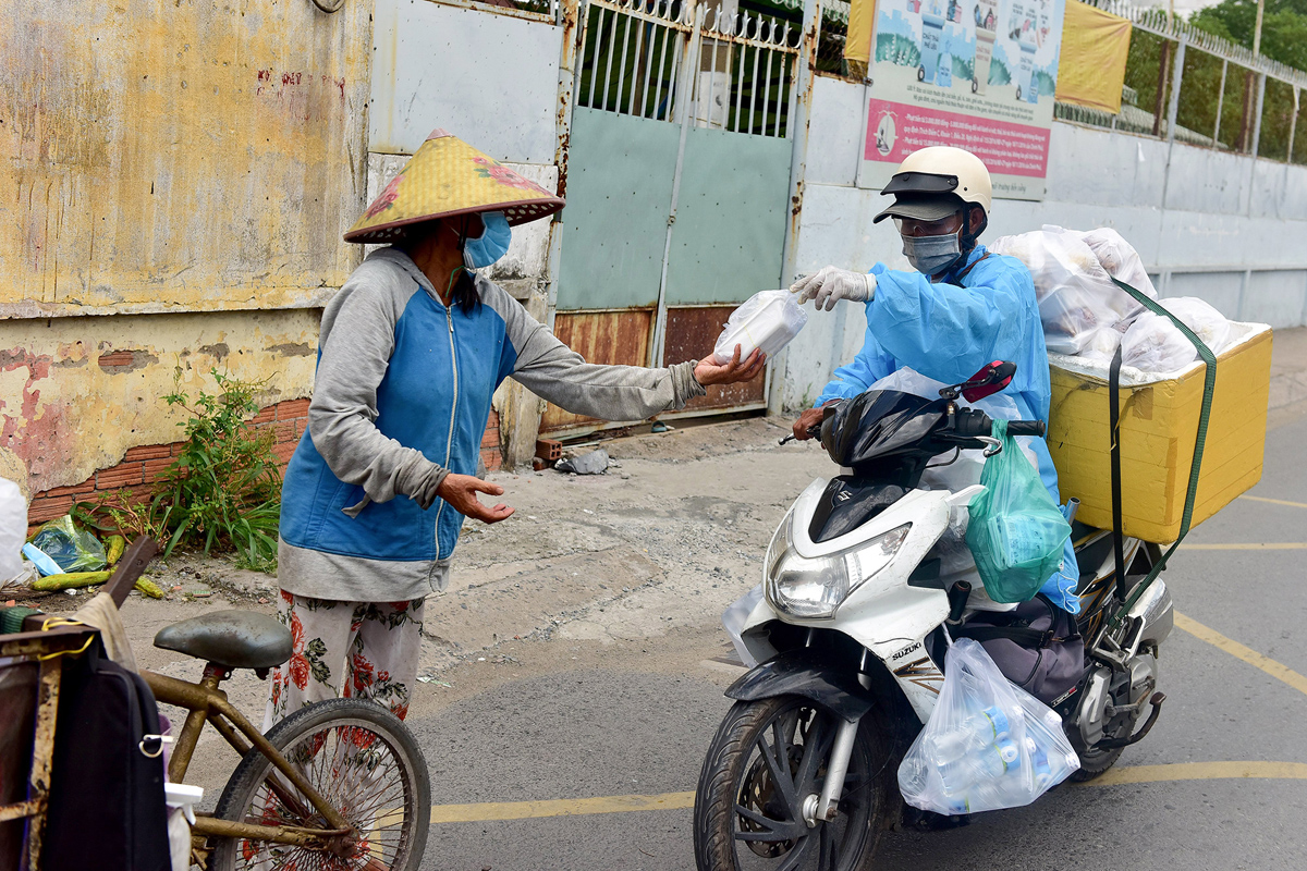 Ông gặp những người làm nghề lượm ve chai liền dừng lại trao những phần cơm cho họ.